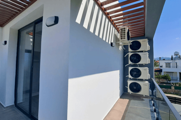 Exterior HVAC units discreetly mounted on the side wall near terrace stairs.