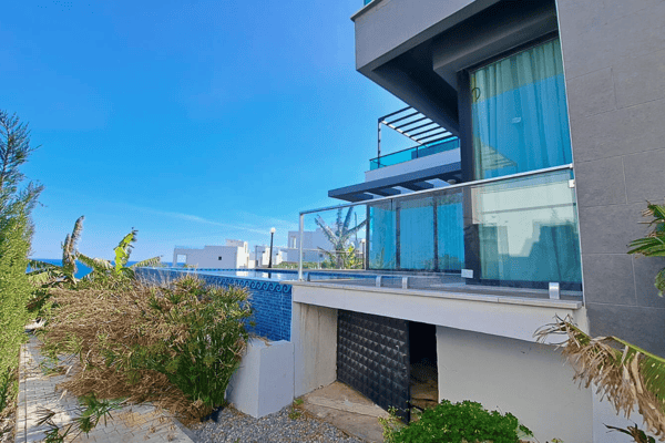 Expansive view blending glistening pool and sleek glass architecture, inviting a seamless coastal lifestyle.