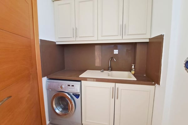 Utility room with laundry setup and integrated cabinetry, maintaining discreet efficiency in a dedicated service space.