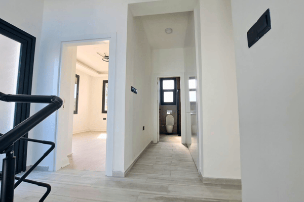 Interior hallway leading to front entrance with wide view and neutral walls.