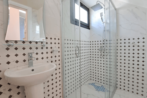 Minimalist bathroom with mosaic tiles and glass shower enclosure, offering a sleek and efficient design.