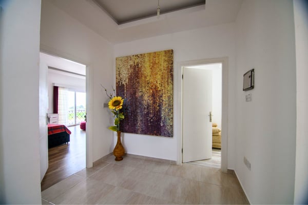 Simple hallway with artistic accents and light tones leading to bedrooms and private living areas.