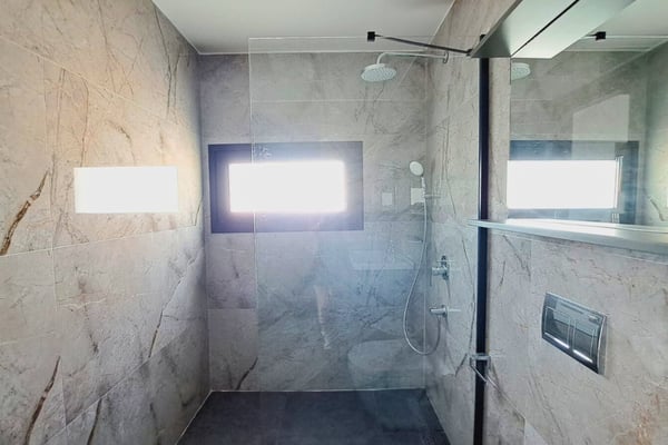 Marble-finished bathroom with built-in cabinetry and horizontal window bringing daylight while preserving privacy.