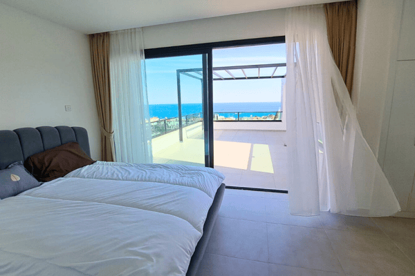 Bedroom with flowing curtains and panoramic sea views, radiating a breezy, beach-inspired charm.