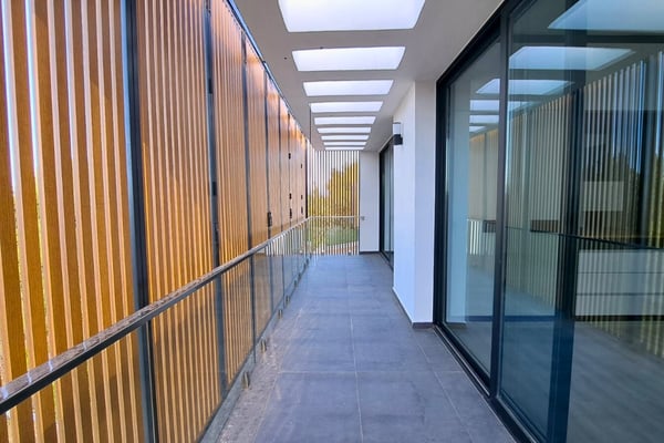 Hallway with vertical wooden wall features and windows on both sides, offering a bright and stylish transition space.