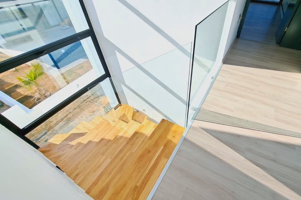 Floating staircase with wood steps and glass railing, emphasizing architectural finesse and a bright open layout.
