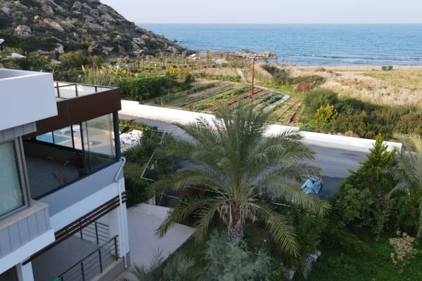 Esentepe villa with an extended terrace and seamless indoor-outdoor flow, overlooking the blue Mediterranean and rugged coastal scenery.