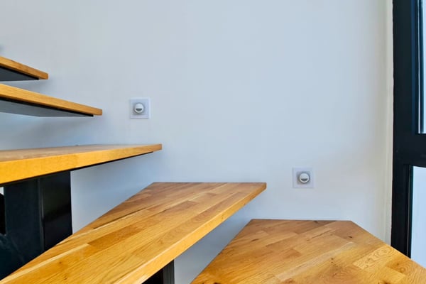 Alternate staircase perspective showing natural wood tones and floating design that enhances open living space.