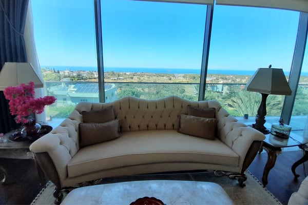 Luxury Bedroom with High Windows and Ambient Lighting – A well-designed bedroom or lounge with a sophisticated tray ceiling, recessed lighting, a large bed or seating area, and tall windows draped in elegant curtains.