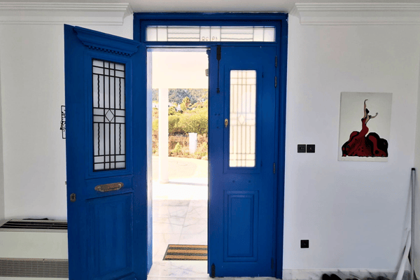 Same blue doors opened, revealing bright light and entry into the home.