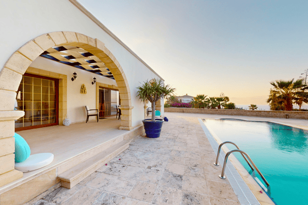 Shaded lounge zone under a tiled pergola next to the pool, merging indoor comfort with open-air luxury.