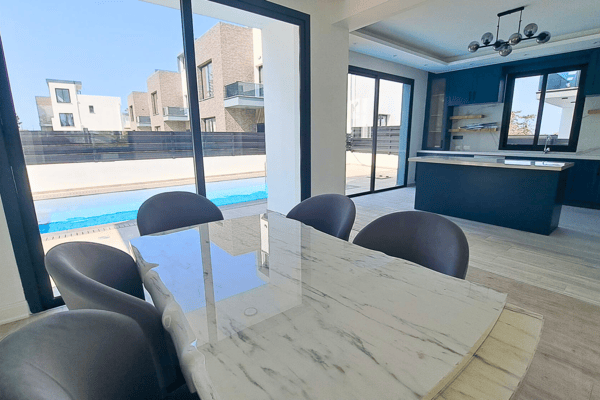 Open plan view showing kitchen island and dining/living flow toward the pool.