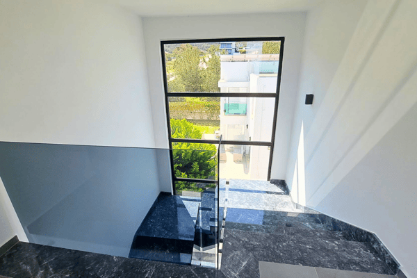 Landing space filled with daylight and enclosed by contemporary glass balustrades.