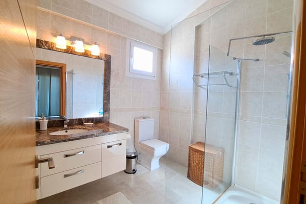 Stone-topped vanity and sconce lights in secondary bath, creating a calming, spa-inspired experience.