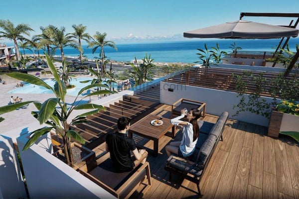 High vantage rooftop shot capturing jacuzzi and elegant lounge setup within open-air leisure space overlooking the coastline.