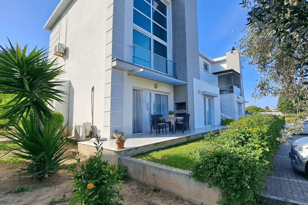 Modern townhouse facade with glass balconies and drought-tolerant garden, showcasing sleek architectural design and curb appeal.