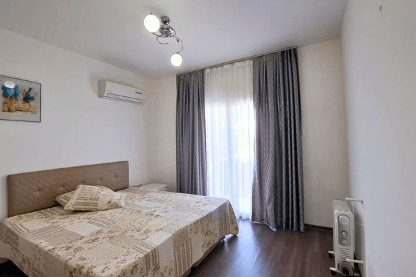 Secondary bedroom with garden-facing doors, blackout curtains and calming decor, designed for comfort and privacy.