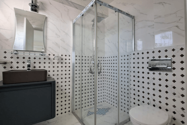 Spacious bathroom with wide vanity and mirror, highlighted by mosaic patterns and soft, diffused light.