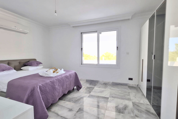 Bedroom with purple accents and marble flooring.