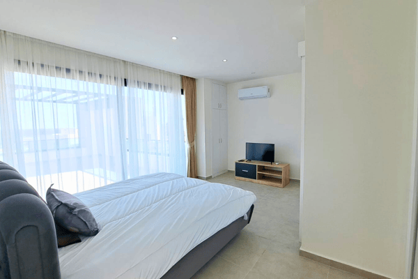 Cozy bedroom featuring a modern bed, soft curtains, and window views that infuse the space with comfort.