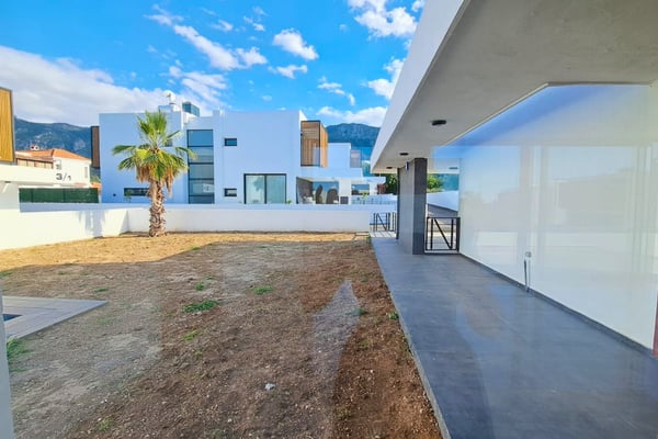Rear garden with large open space, privacy walls, and newly landscaped areas offering seclusion and modern outdoor potential.