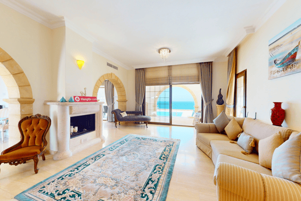 Spacious living room with cream sofas, ornate rug, fireplace, and archways reflecting local architectural motifs.