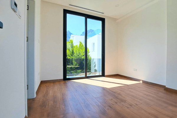 Bedroom with balcony access, warm wood floors, and generous natural light.