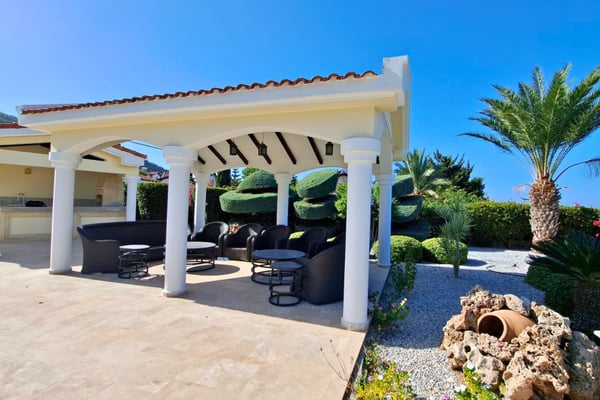 Lattice-shaded side veranda and carport surrounded by tropical greenery and finished in durable materials for long-term use.