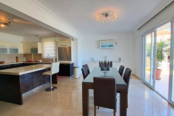 Kitchen and dining nook with granite counters, high-gloss cabinetry and ambient lighting setting a contemporary tone.