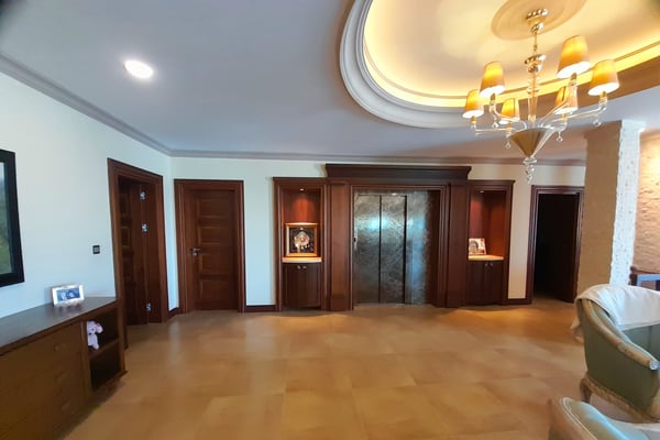 Luxury Bedroom with Spacious Seating and Elegant Design – A refined bedroom or lounge featuring a plush bed or seating arrangement, tall windows with drapes, a stylish tray ceiling, and sleek wood or tile floors.