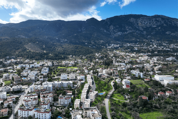 Wide aerial image incorporating nearby settlements and mountain terrain, reinforcing the property's connection with nature.