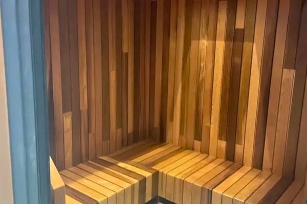 Cozy wooden sauna interior with ambient lighting, featuring smooth panels and corner seating.