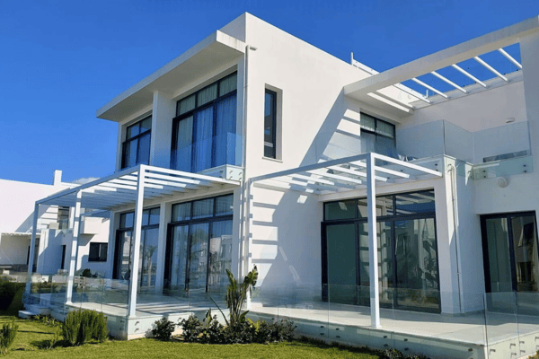 Side view of sleek villa with pergola shade and curated plants, showcasing architectural refinement and outdoor comfort.
