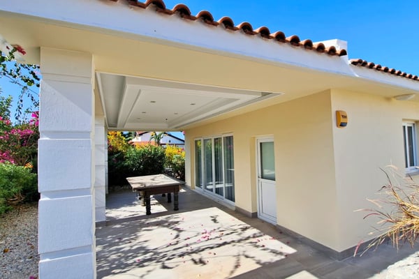 Rear veranda framed by white columns, offering private, shaded outdoor seating connected to the garden and ground-floor rooms.
