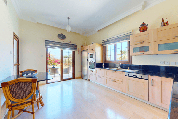 Fully equipped kitchen with natural wood cabinetry, modern appliances, and large windows.