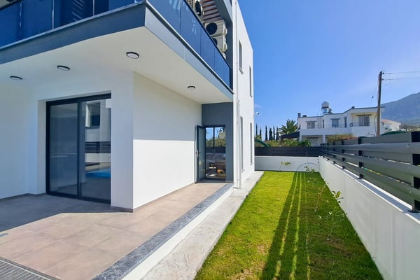Sliding glass doors connecting interior living space with outdoor garden and lawn.