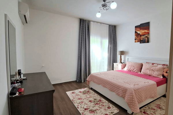 Primary bedroom with balcony doors, soft tones, and tasteful furniture, offering restful living and cozy aesthetics.