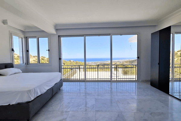 Bedroom with double bed, floor-to-ceiling windows, and scenic views.