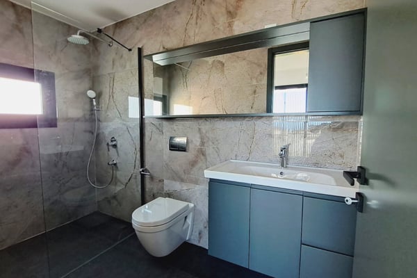 Stylish modern bathroom with premium stone finishes, contemporary fixtures, and natural lighting through small window.