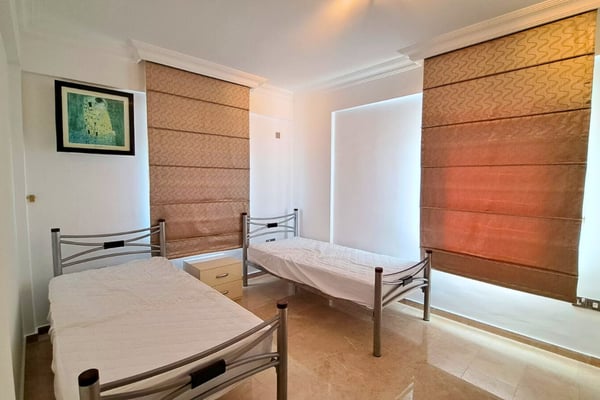 Twin bedroom with neutral palette and practical layout, suitable for flexible uses including guest or office space.