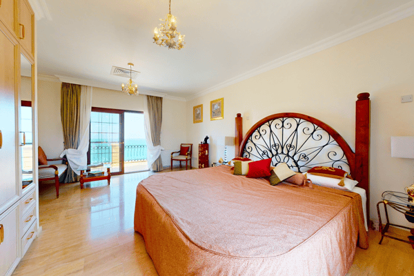 Bedroom with a dramatic red-wood headboard and natural light pouring in through patio doors.