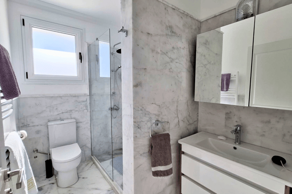 Bathroom with toilet, under-sink storage, and marble wall panels.