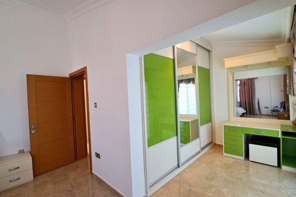 Youthful bedroom with lime-green tiled bathroom entry and open shelving, adding energy and color to private space.