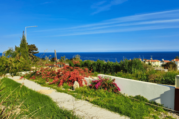 Scenic garden paths lead through blooming flora toward sweeping coastal vistas that define tranquil island living.