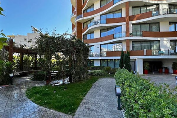 Modern apartment complex framed by vibrant gardens and open walkways, blending clean lines with inviting community spirit.