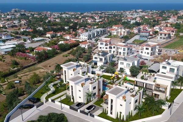 Aerial rendering of luxury villa community with private pools, gardens, and coastal hillside layout.