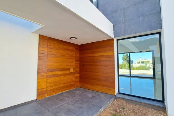 Entry area with wooden front door and polished flooring, combining luxury elements with welcoming contemporary design.