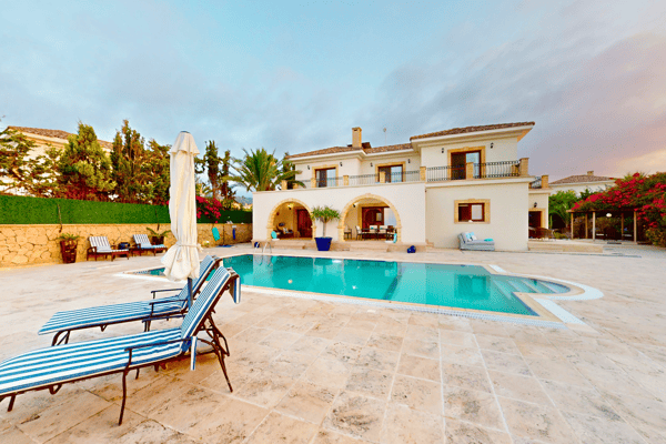Full property courtyard shot, highlighting the pool in the foreground and the villa’s symmetrical structure behind.