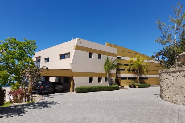 Mediterranean Home with Multi-Car Garage – The front of this luxurious home showcases a wide driveway, multi-car garage, Mediterranean-style stucco walls, tile roofing, and elegant arched entryways.