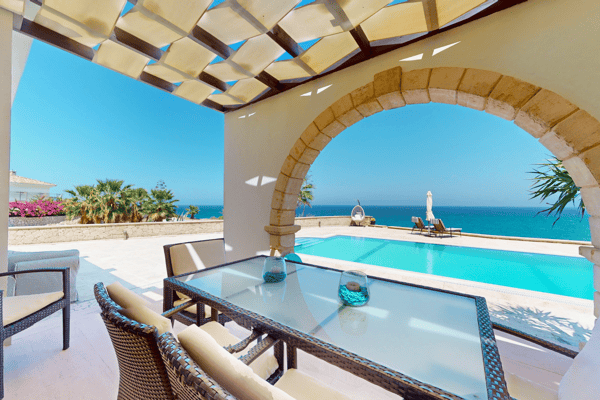 Covered veranda with exposed beams and seaside views, perfect for alfresco dining or shaded relaxation.